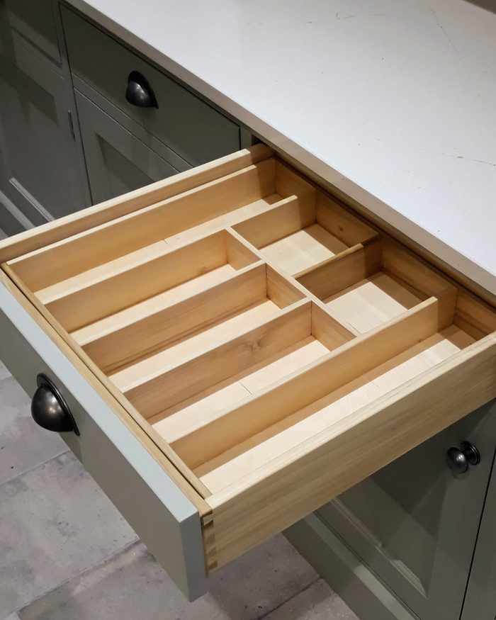 A dovetailed drawer pulled open, fitted with a tray of maple cutlery dividers
