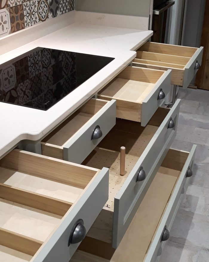 A run of hand-painted drawers pulled open, showing the pegged plate drawer and the boxes behind the fronts